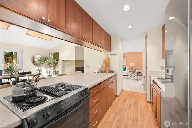 kitchen with electric range, recessed lighting, light countertops, brown cabinets, and light wood finished floors