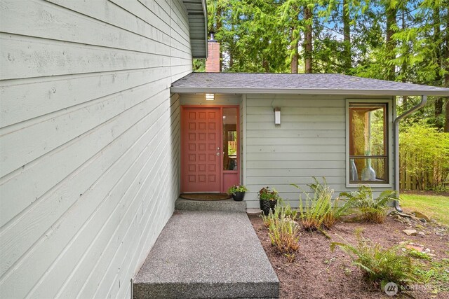 view of exterior entry featuring a shingled roof