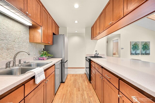 kitchen with light countertops, appliances with stainless steel finishes, a sink, and light wood-style flooring