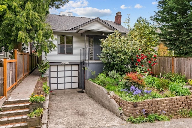 bungalow featuring fence, roof with shingles, an attached garage, a chimney, and concrete driveway