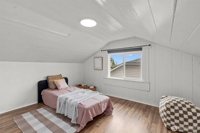 bedroom with baseboards, lofted ceiling, and wood finished floors