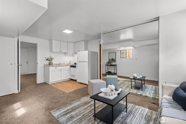 living area featuring baseboards and light carpet
