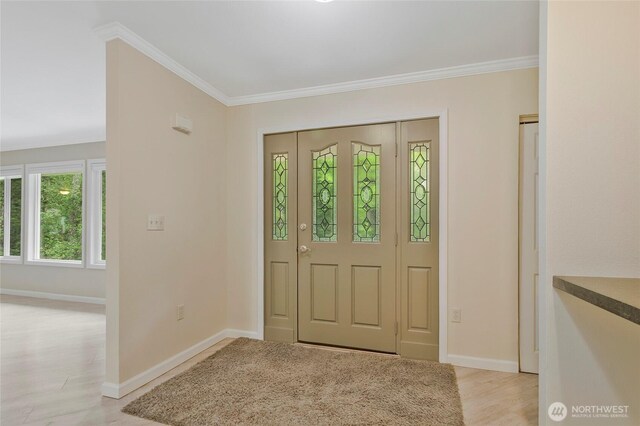 entrance foyer featuring baseboards, ornamental molding, and light wood-style floors