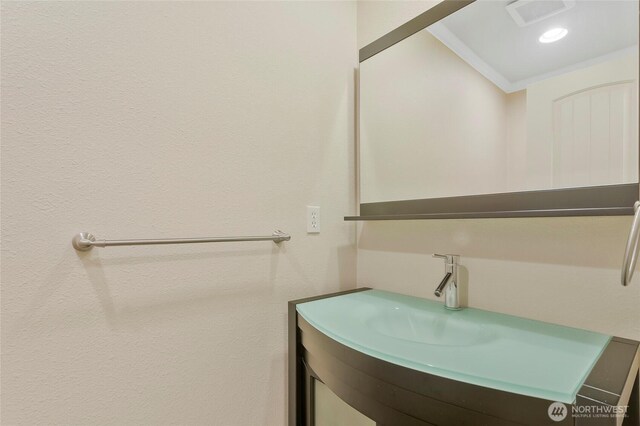 bathroom featuring crown molding, vanity, and visible vents