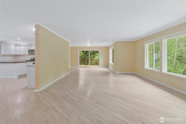 unfurnished living room with baseboards, recessed lighting, light wood-style floors, and ornamental molding