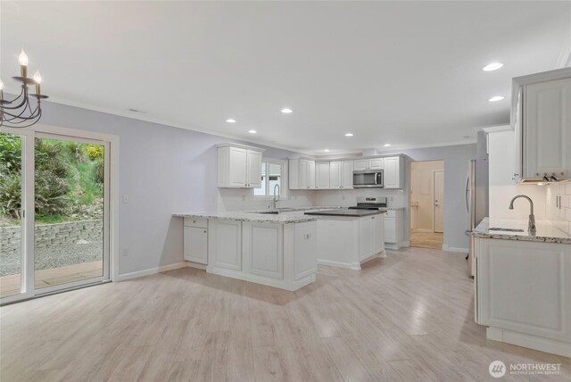 kitchen with baseboards, light wood-type flooring, recessed lighting, a sink, and stainless steel appliances