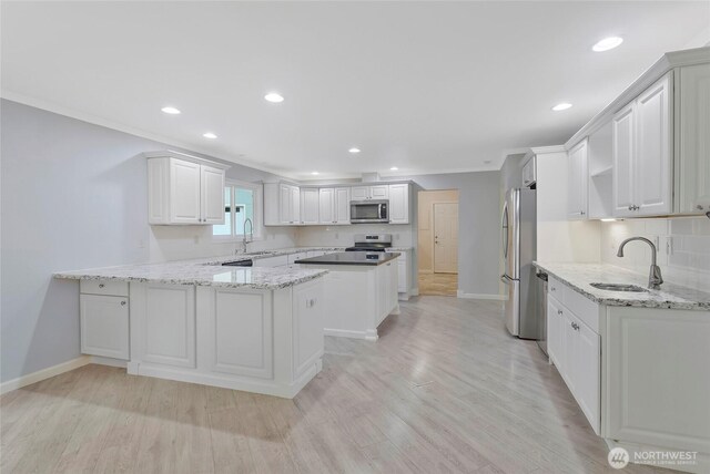 kitchen featuring stainless steel appliances, baseboards, a sink, and a peninsula
