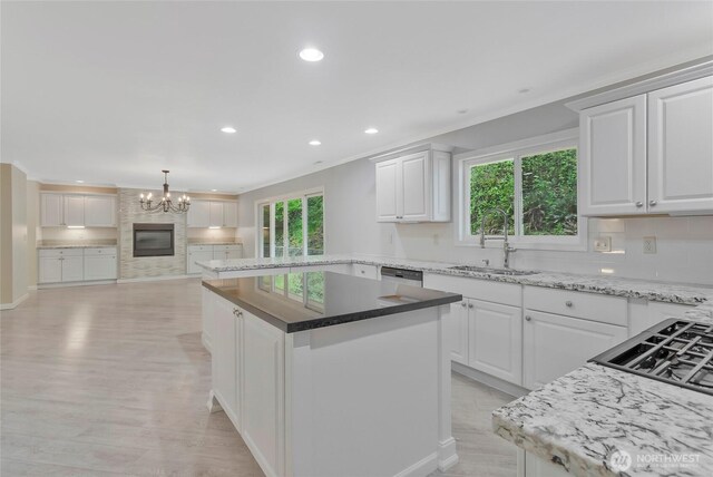 kitchen with a kitchen island, white cabinetry, a chandelier, a sink, and backsplash