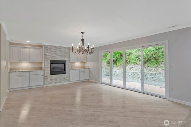 unfurnished living room with baseboards, ornamental molding, and light wood-style flooring