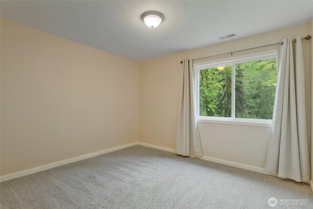 carpeted spare room featuring baseboards and visible vents