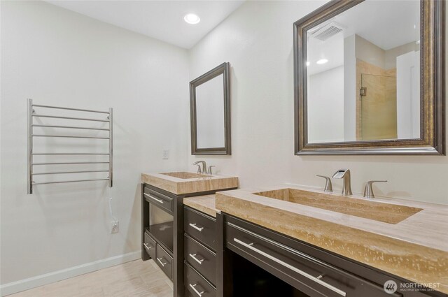 full bath featuring radiator heating unit, visible vents, a sink, and two vanities