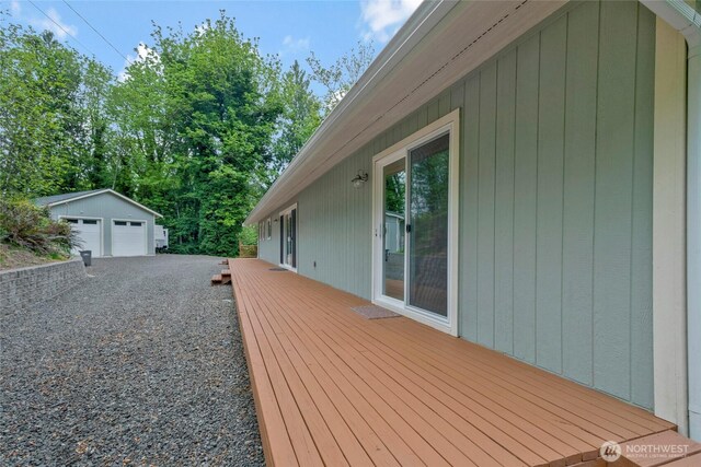 wooden terrace featuring a detached garage and an outbuilding