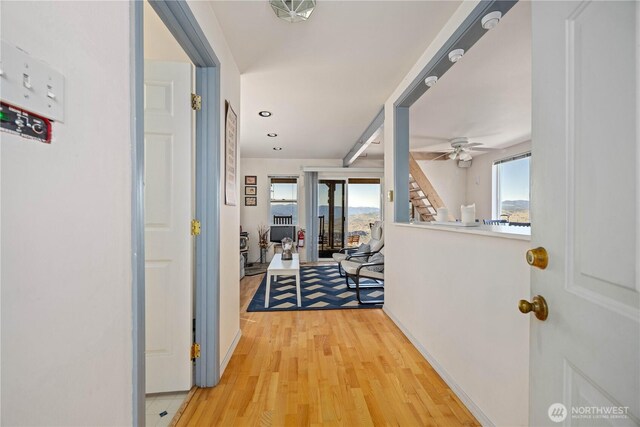 hallway featuring plenty of natural light, light wood-style flooring, and baseboards
