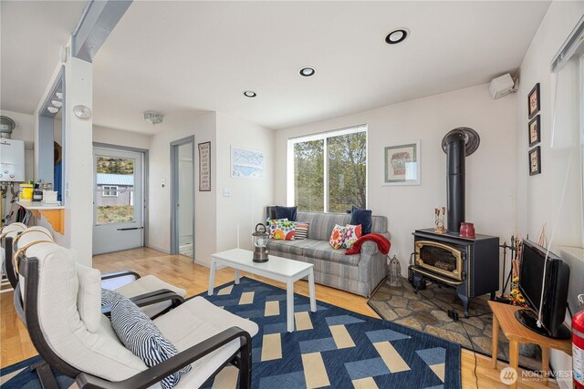 living area featuring recessed lighting, a wood stove, light wood finished floors, and a wealth of natural light