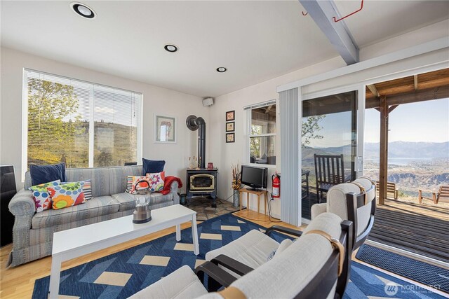 living area featuring recessed lighting, plenty of natural light, light wood-style flooring, and a wood stove