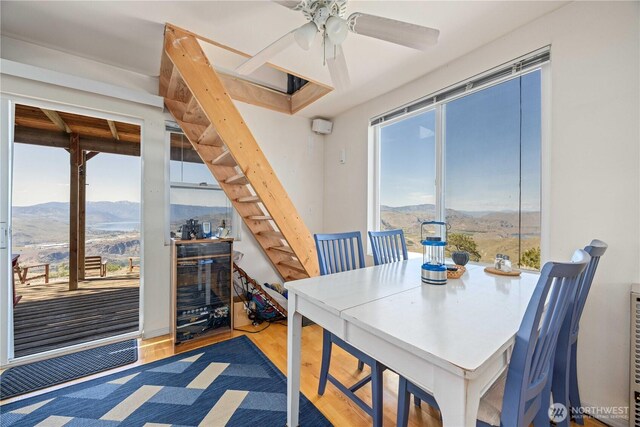 dining area with stairs, ceiling fan, a mountain view, and wood finished floors
