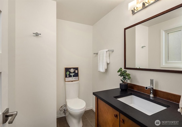 half bath with tile patterned flooring, toilet, vanity, and baseboards