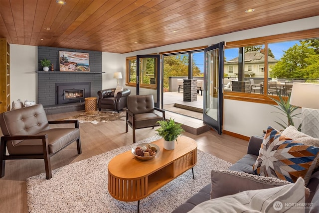 living area with wood ceiling, recessed lighting, healthy amount of natural light, wood finished floors, and a brick fireplace