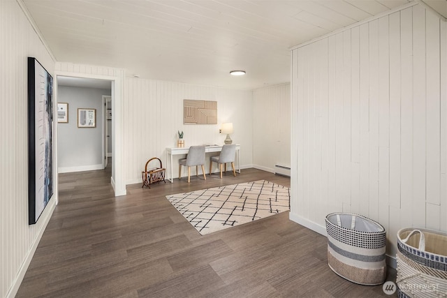 hallway with wood finished floors, baseboard heating, wood walls, and baseboards