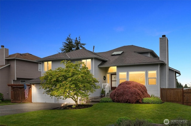 split level home featuring a garage, fence, a front yard, a chimney, and driveway