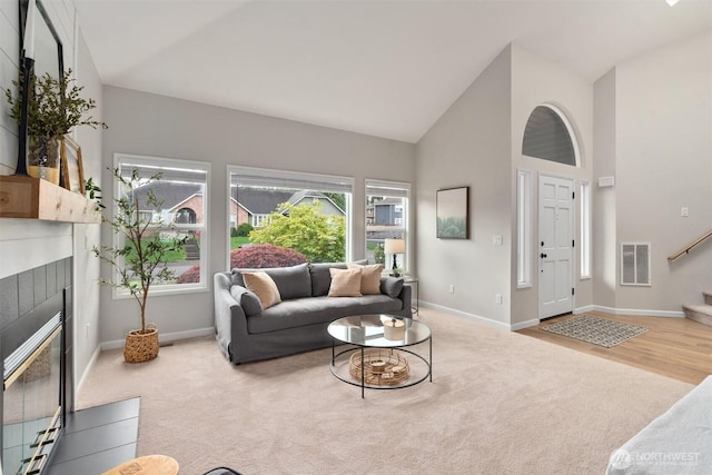 living room with baseboards, carpet flooring, high vaulted ceiling, and a tile fireplace