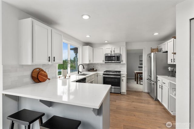 kitchen featuring a sink, appliances with stainless steel finishes, recessed lighting, and a peninsula