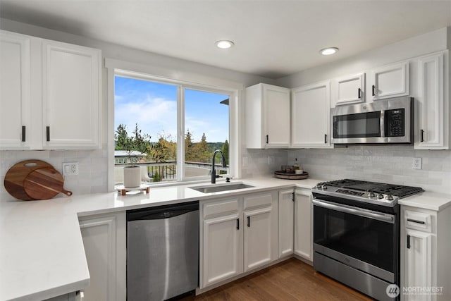 kitchen with tasteful backsplash, a sink, light countertops, white cabinets, and stainless steel appliances