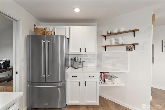 kitchen featuring decorative backsplash, white cabinetry, high end refrigerator, light countertops, and light wood-style flooring