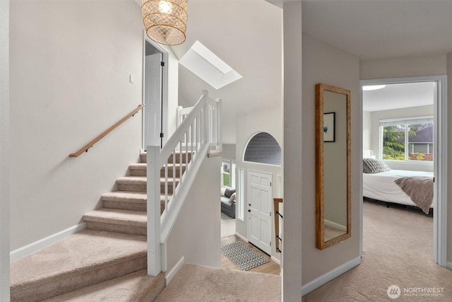 staircase with a skylight, baseboards, and carpet flooring