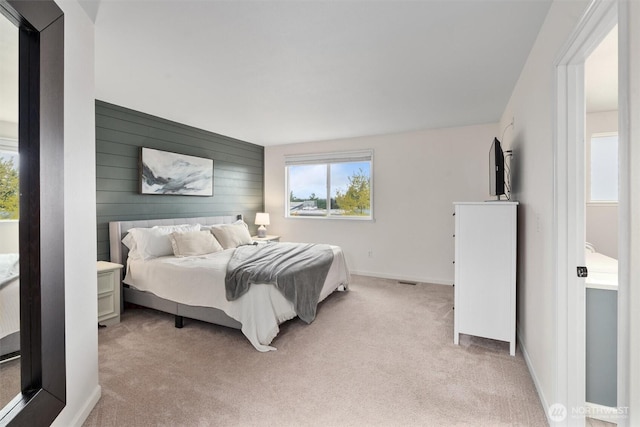 bedroom with baseboards, wood walls, and light carpet