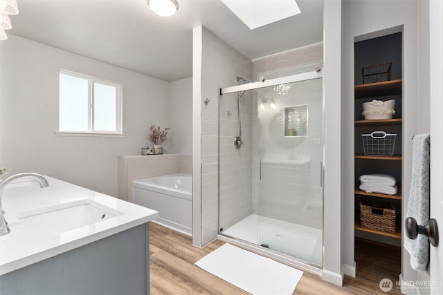 bathroom with a skylight, a shower stall, and wood finished floors