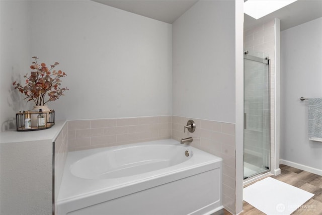 full bath featuring a bath, a shower stall, and wood finished floors