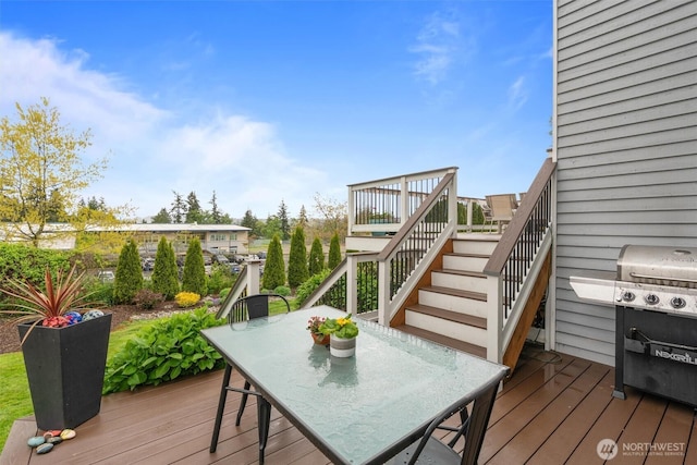 deck featuring outdoor dining area, stairway, and area for grilling