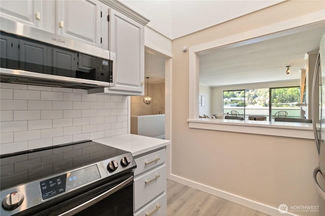 kitchen with decorative backsplash, baseboards, light wood-style floors, light countertops, and appliances with stainless steel finishes