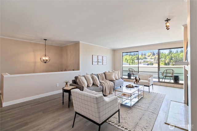 living area featuring baseboards, an inviting chandelier, ornamental molding, and wood finished floors