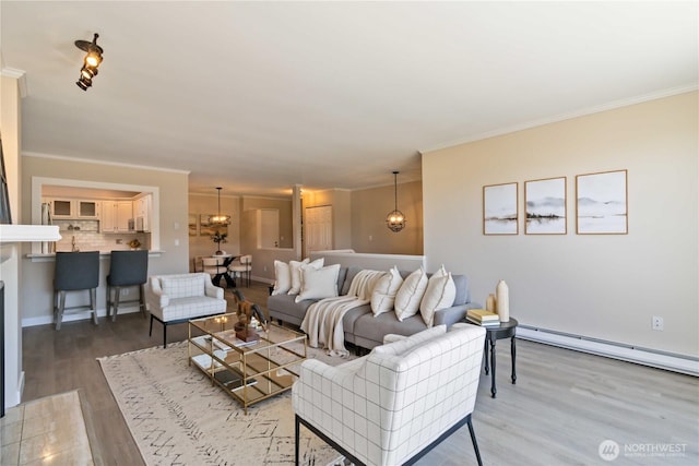 living area with ornamental molding, baseboard heating, and wood finished floors