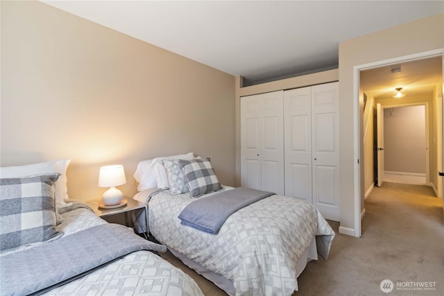 carpeted bedroom featuring baseboards and a closet