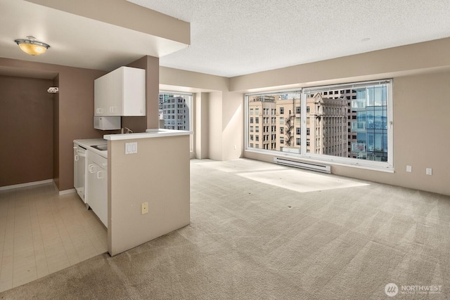 kitchen with a textured ceiling, baseboard heating, white cabinets, dishwashing machine, and light carpet