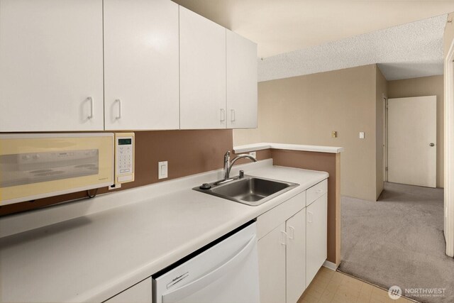 kitchen with a sink, white cabinets, and white appliances
