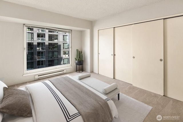 bedroom featuring a closet, a textured ceiling, carpet, and baseboard heating
