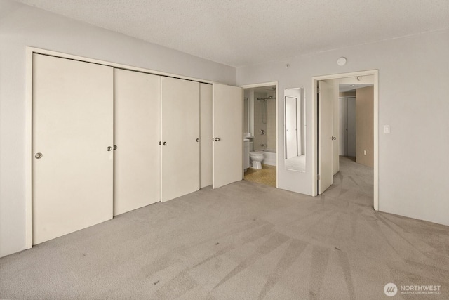 unfurnished bedroom with a closet, connected bathroom, and light carpet