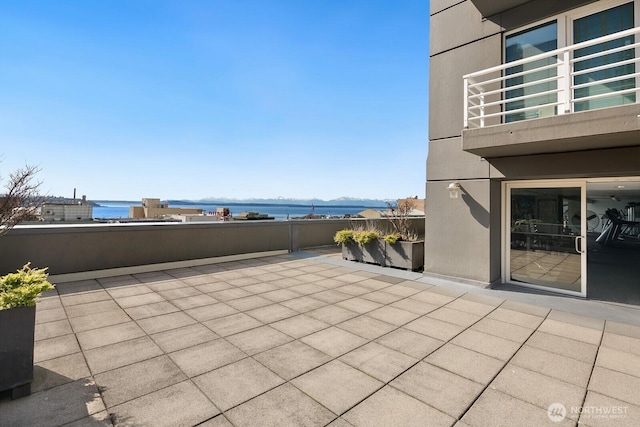 view of patio / terrace with a water view, fence, and a balcony