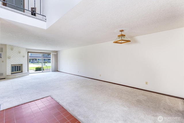 unfurnished living room with carpet floors, a textured ceiling, baseboards, and a fireplace