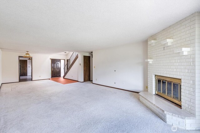 unfurnished living room with carpet floors, a fireplace, baseboards, stairway, and a textured ceiling