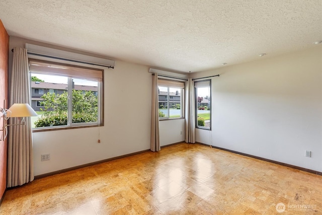 unfurnished room with baseboards and a textured ceiling