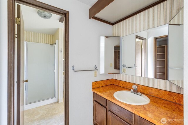 bathroom with wallpapered walls, walk in shower, and vanity
