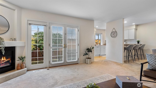 living room featuring carpet flooring, a glass covered fireplace, recessed lighting, baseboards, and visible vents
