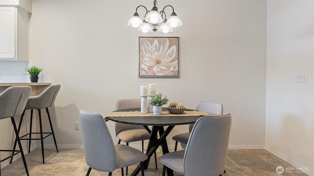 dining area featuring baseboards, a notable chandelier, and light carpet