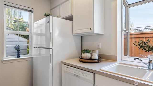 kitchen featuring white appliances, white cabinets, a sink, and light countertops