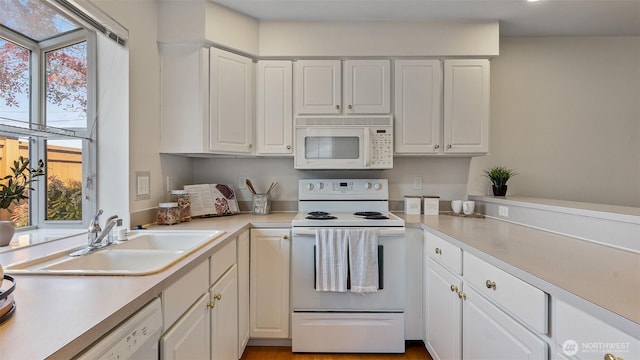 kitchen featuring a sink, white cabinets, white appliances, and light countertops